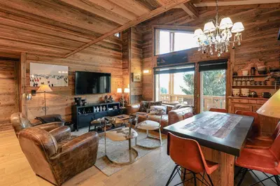 a living room with wooden walls and a table and chairs at Le Duplex in Megève