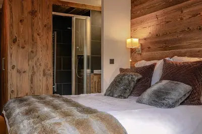 a bedroom with a bed with a wooden wall at Le Duplex in Megève
