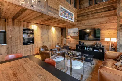 a living room with a glass table and leather chairs at Le Duplex in Megève