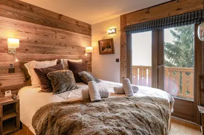 a bedroom with a large bed with a wooden wall at Le Duplex in Megève