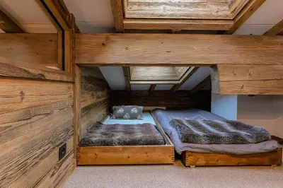 a bed in a room with wooden walls at Le Duplex in Megève