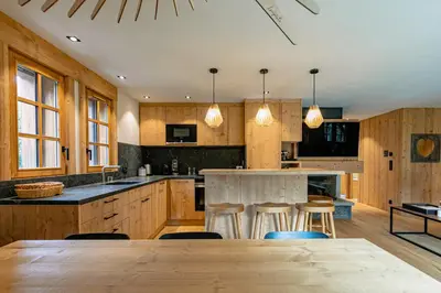a kitchen with wooden cabinets and a bar with stools at Escapade in Megève