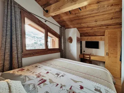 a bedroom with a bed and a window and a television at Les Mesanges in Megève