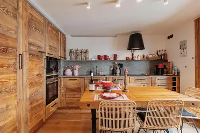 a kitchen with wooden cabinets and a wooden table with chairs at Les Mesanges in Megève