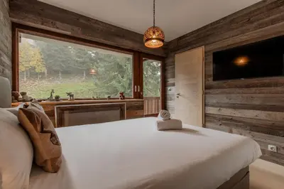 a bedroom with a large bed and a large window at Red Touch - Balcon vue et confort en famille in Megève