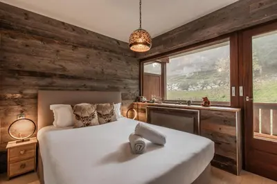 a bedroom with a large white bed and wooden walls at Red Touch - Balcon vue et confort en famille in Megève