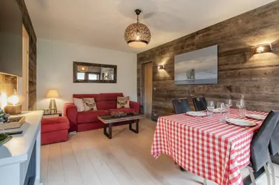 a living room with a table and a red couch at Red Touch - Balcon vue et confort en famille in Megève