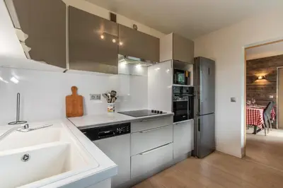 a white kitchen with a sink and a counter at Red Touch - Balcon vue et confort en famille in Megève