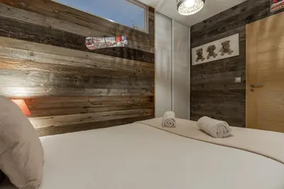 a bedroom with a white bed and wooden wall at Red Touch - Balcon vue et confort en famille in Megève