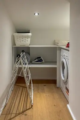 a laundry room with a ladder next to a washing machine at Le Black Wood in Demi-Quartier