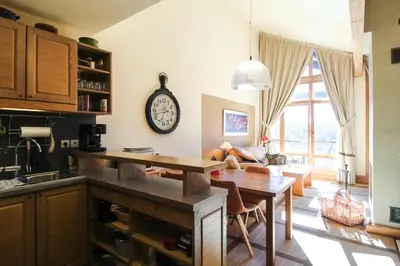 a kitchen with a table and a clock on the wall at Residence Terrasses Eos, T2 48m2 Sud, Vue Montagne, avec Cheminee, Parking, Piscine in Flaine