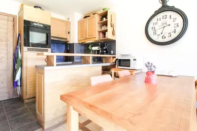 a kitchen with a wooden table and a clock on the wall at Residence Terrasses Eos, T2 48m2 Sud, Vue Montagne, avec Cheminee, Parking, Piscine in Flaine