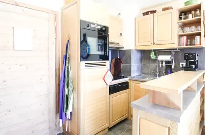 a kitchen with wooden cabinets and a stove top oven at Residence Terrasses Eos, T2 48m2 Sud, Vue Montagne, avec Cheminee, Parking, Piscine in Flaine