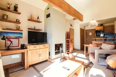 a living room with a couch and a tv at Residence Terrasses Eos, T2 48m2 Sud, Vue Montagne, avec Cheminee, Parking, Piscine in Flaine