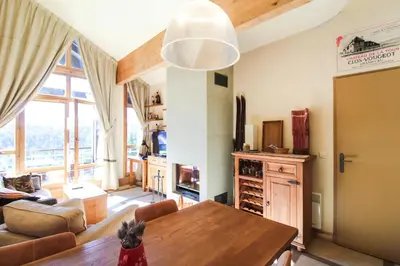 a living room with a table and a large window at Residence Terrasses Eos, T2 48m2 Sud, Vue Montagne, avec Cheminee, Parking, Piscine in Flaine