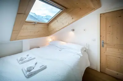 a bedroom with a white bed with a window at Rupicapra apartment - Chamonix All Year in Chamonix-Mont-Blanc