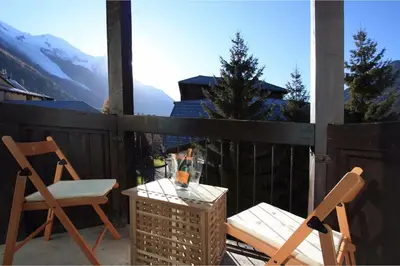 a patio with two chairs and a table with a glass at Rupicapra apartment - Chamonix All Year in Chamonix-Mont-Blanc