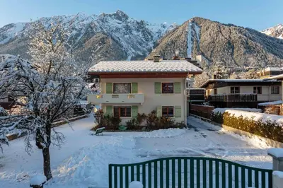 a house with two cars parked in a parking lot at Edelweiss apartment - Chamonix All Year in Chamonix-Mont-Blanc