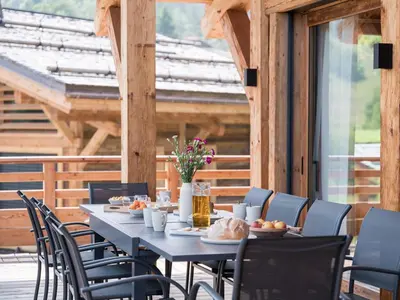 a table with chairs and food on it on a patio at Chalet Victory I Le Chalet Club in Combloux