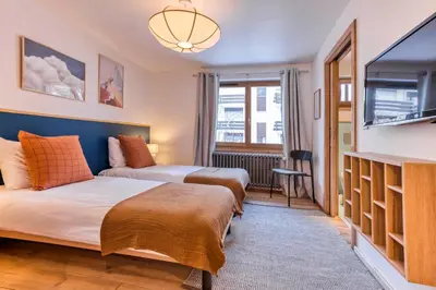 two beds in a room with a flat screen tv at AO HOUSE - Chalet PAN BENA in Les Houches
