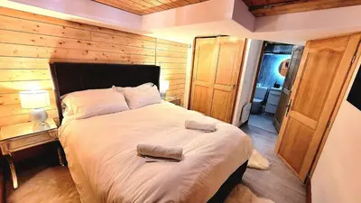 a bedroom with a large bed with a wooden wall at Ski in Ski out MNT Direct piste access in Les Houches