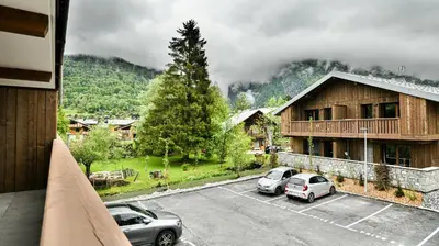 a building with cars parked in a parking lot at Le Sève - B103 in Samoëns