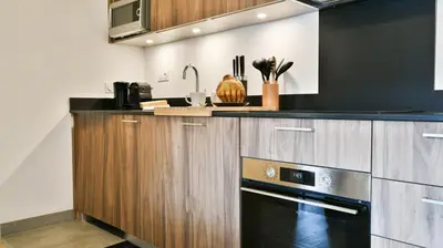 a kitchen with wooden cabinets and a black stove at Le Sève - B103 in Samoëns