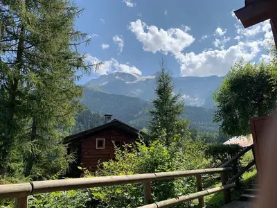 a wooden house on a hill with mountains in the background at Contamines-Monjoie in Les Contamines-Montjoie