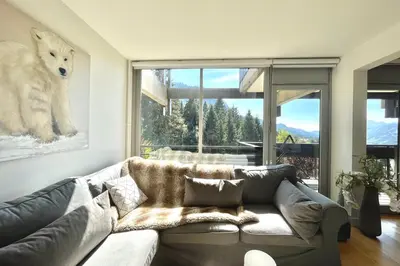 a living room with a couch and a large window at Le Repère de l'Ours in Megève