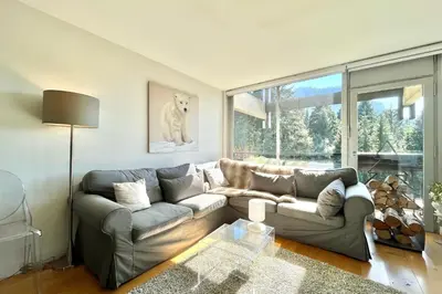 a living room with a couch and a large window at Le Repère de l'Ours in Megève