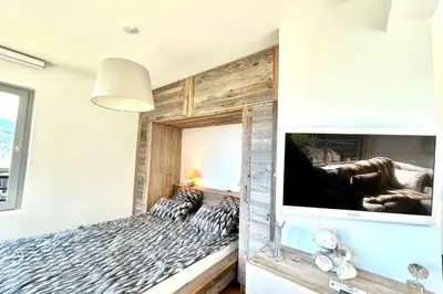 a bedroom with a wooden wall with a bed and a tv at Le Repère de l'Ours in Megève