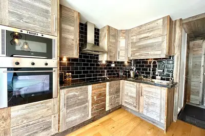 a kitchen with wooden cabinets and a stove top oven at Le Repère de l'Ours in Megève