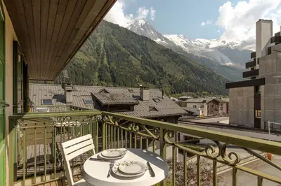 a table and chairs on a balcony with a view of mountains at Blanc Neige in Chamonix-Mont-Blanc