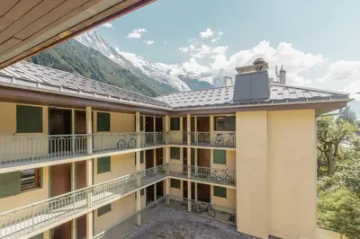 a building with balconies and mountains in the background at Blanc Neige in Chamonix-Mont-Blanc