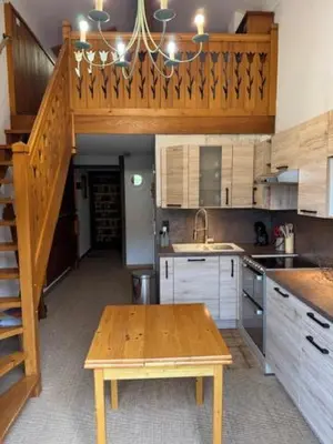 a kitchen with a wooden table and a staircase at Le chalet des pistes in Demi-Quartier