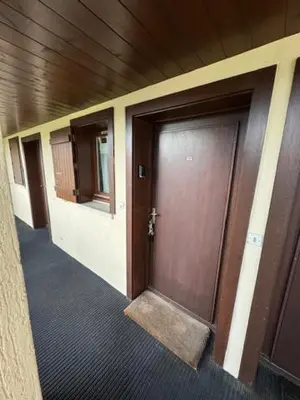 a hallway of a building with a wooden door at Le chalet des pistes in Demi-Quartier