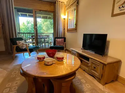 a living room with a table and a television at T4 Duplex à Samoëns, standing avec balcon & parking privé - FR-1-629-149 in Samoëns
