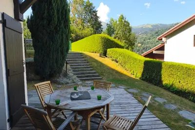 a table and chairs on a patio with a hedge at South-facing flat with garden near city center in Saint-Gervais-les-Bains