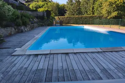 a swimming pool with a wooden deck and blue water at South-facing flat with garden near city center in Saint-Gervais-les-Bains