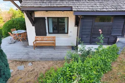 a wooden deck with a bench and a table at South-facing flat with garden near city center in Saint-Gervais-les-Bains