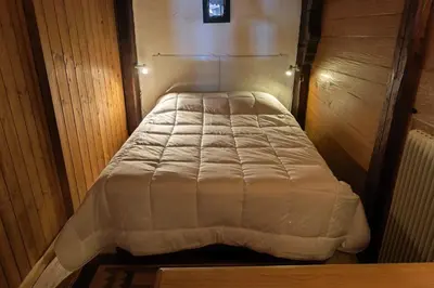 a small bed in a room with wooden walls at South-facing flat with garden near city center in Saint-Gervais-les-Bains
