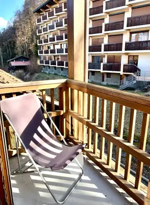 a chair sitting on a balcony with a building at Studio cosy au cœur de la station des Carroz in Arâches-la-Frasse