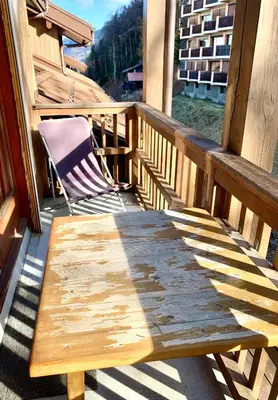a wooden bench sitting on a porch with a chair at Studio cosy au cœur de la station des Carroz in Arâches-la-Frasse