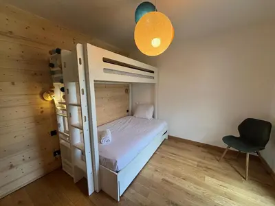 a bedroom with a bunk bed and a chair at Kayla du Mont-Blanc - Espace bien etre - Piscine in Les Houches
