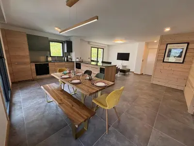a large kitchen with a wooden table and yellow chairs at Kayla du Mont-Blanc - Espace bien etre - Piscine in Les Houches