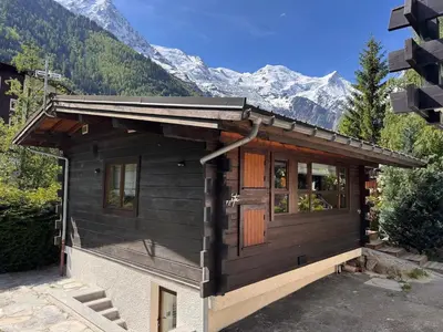 a small cabin with mountains in the background at Chalet Meta by Brennus Chamonix in Chamonix-Mont-Blanc