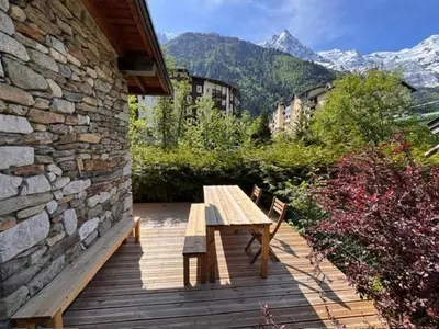 a wooden table and benches on a wooden deck at Chalet Meta by Brennus Chamonix in Chamonix-Mont-Blanc