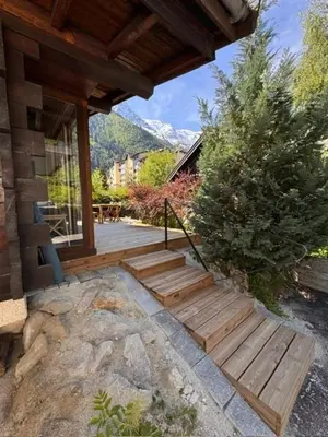 a house with wooden steps leading to a patio at Chalet Meta by Brennus Chamonix in Chamonix-Mont-Blanc