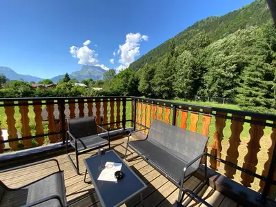 a balcony with two chairs and a table with a view at Hôtel-Bar-Restaurant Les Dômes de Miage in Saint-Gervais-les-Bains