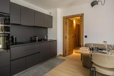 a kitchen with black cabinets and a wooden table at Paradisa Cosmique Moderne 2-bedroom with amazing Mont-Blanc view! in Chamonix-Mont-Blanc